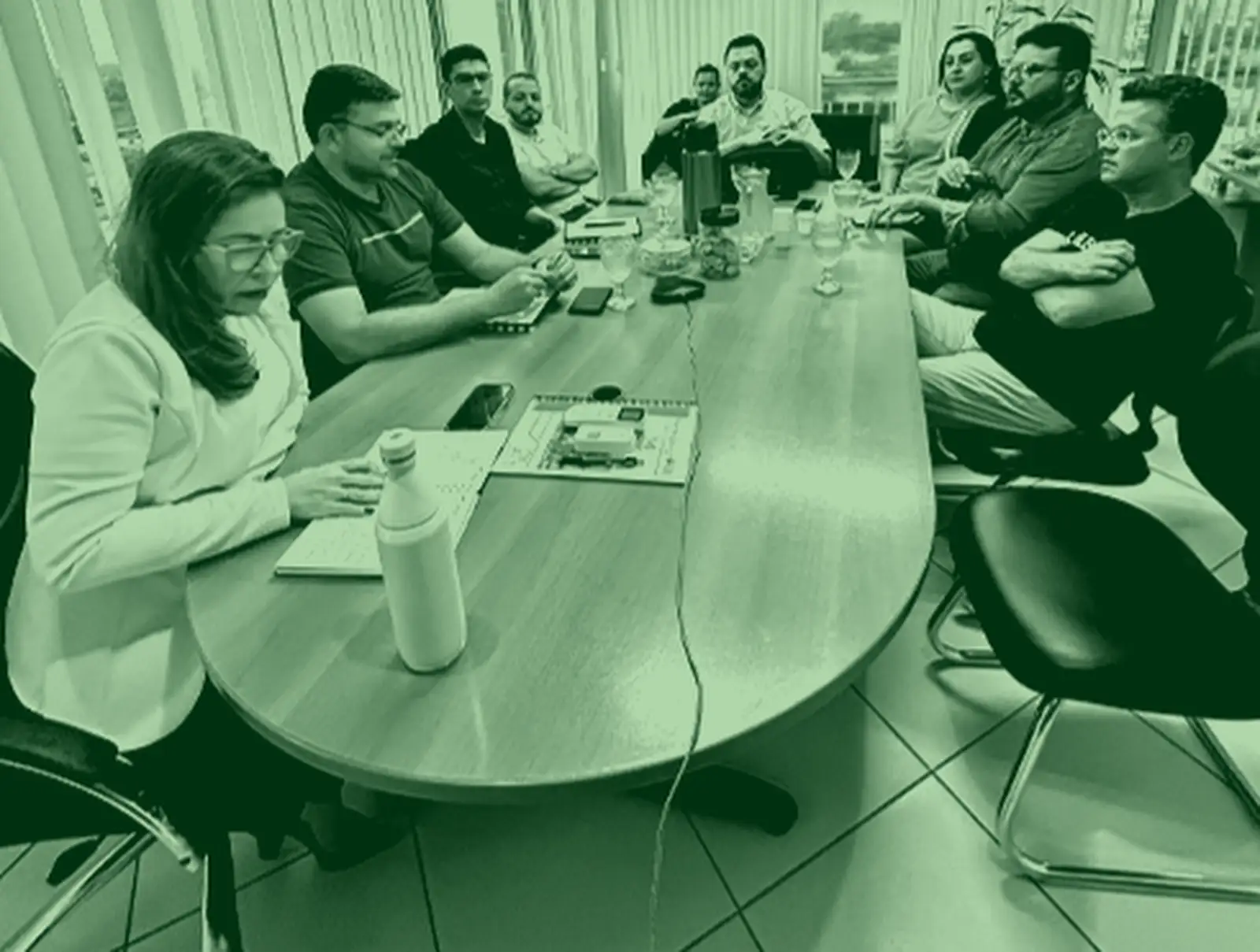 Reunião em torno de uma mesa oval, em foto com tratamento verde