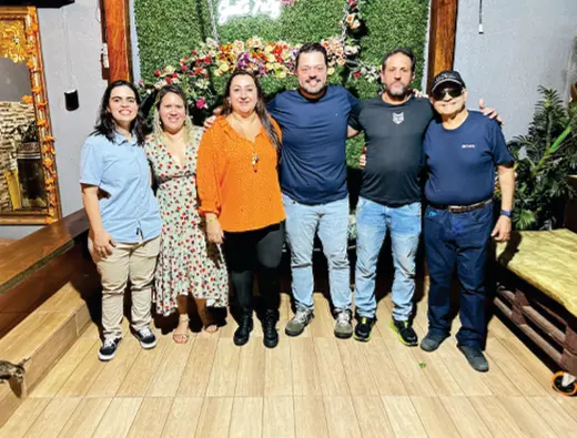 Grupo posa diante de um painel de flores